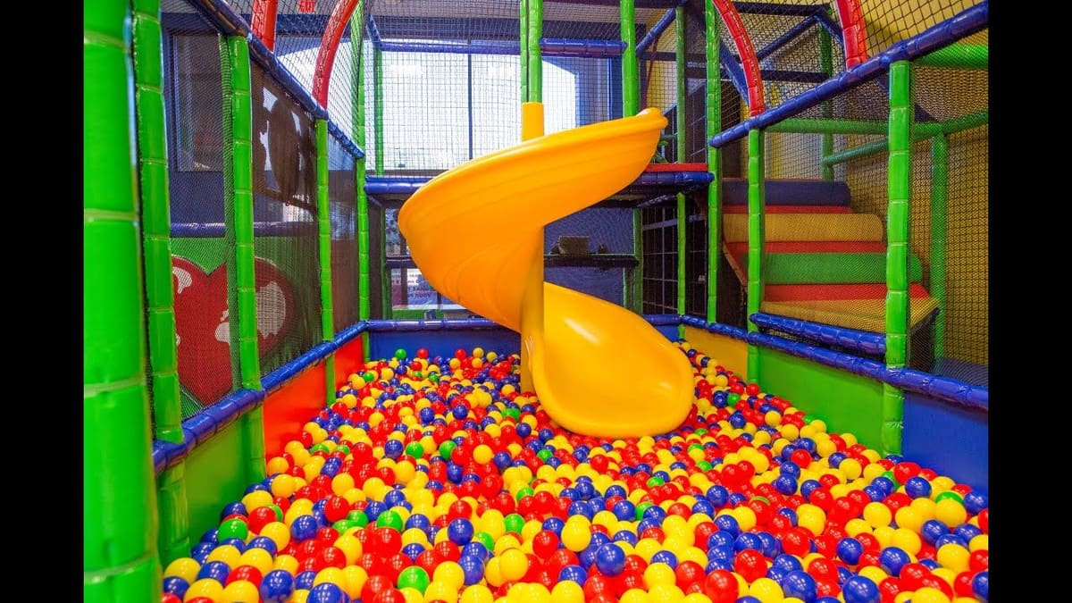 Yellow spiral slide dropping into a ball pit